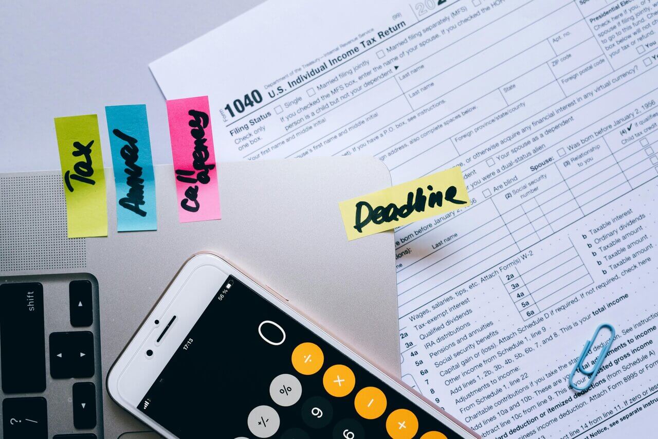 Close up of documents, phone, postit notes with deadline writing