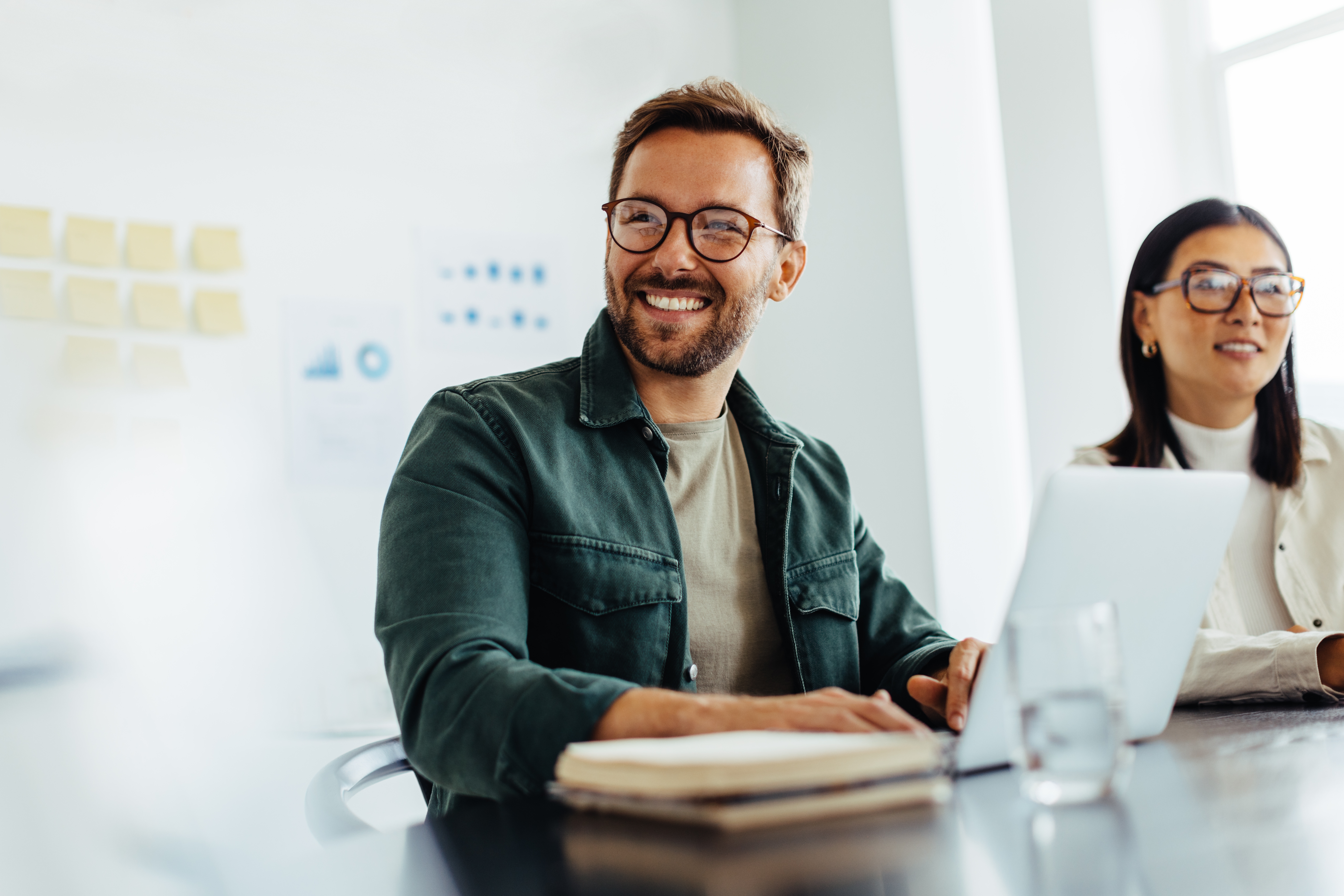 Aspiring male accountant at work smiling beside female colleague 
